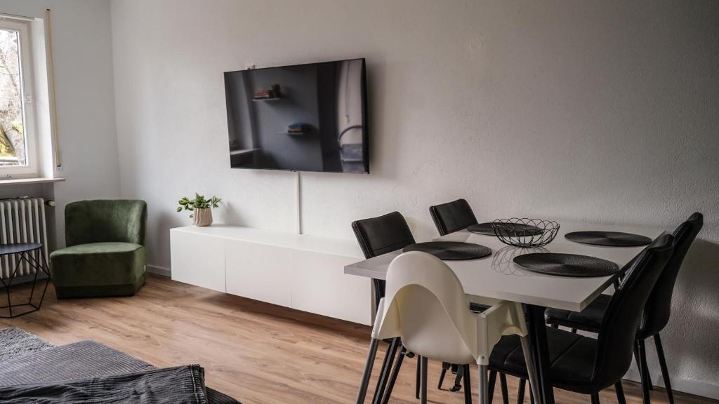 Un comedor con una mesa y un televisor en la pared. en Exklusives Ferien-Appartement mit Pool- und Saunazugang für bis zu 4 Personen, en Schönwald