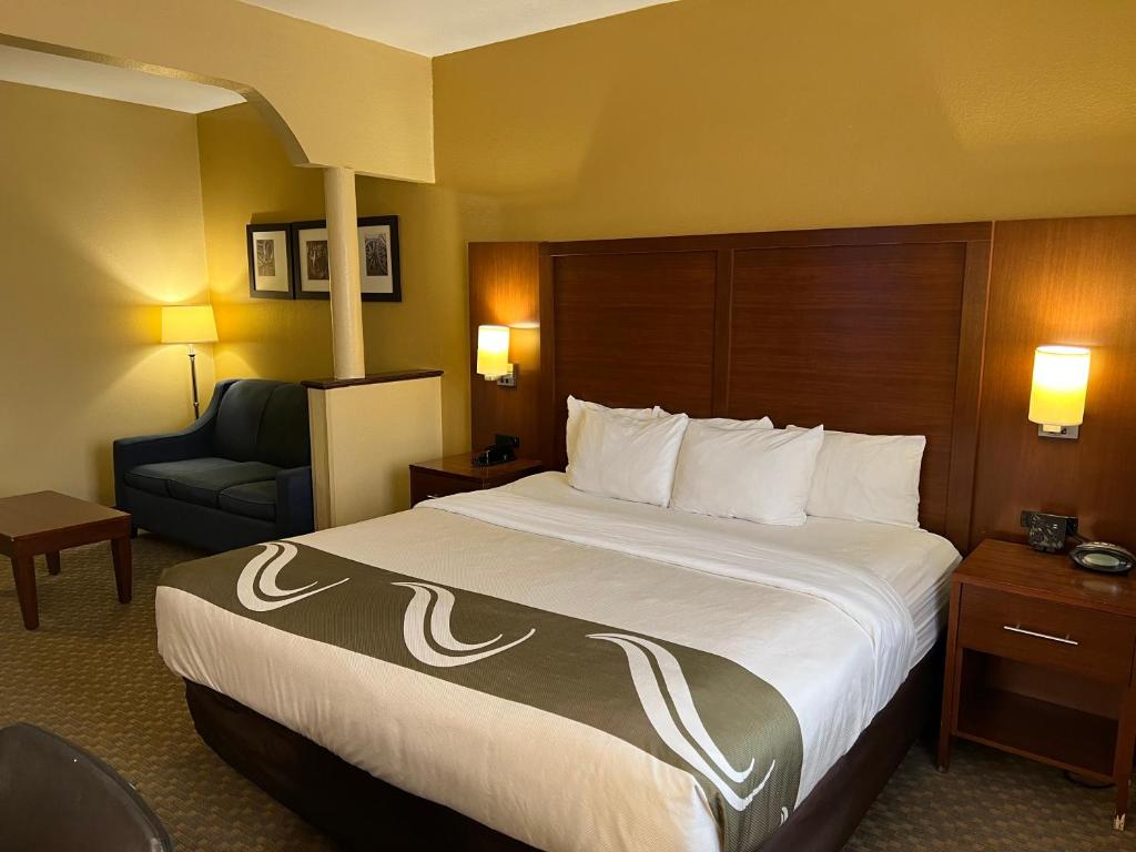 um quarto de hotel com uma cama grande e uma cadeira em Quality Suites Midland North Loop 250 em Midland