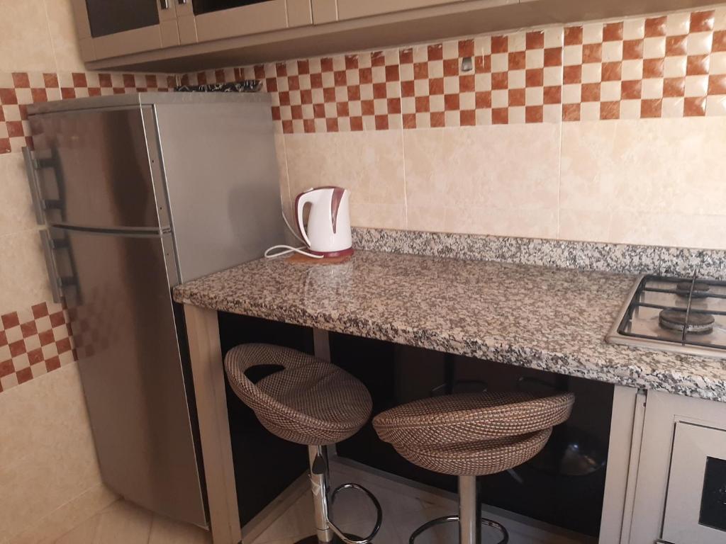 a kitchen with a counter with stools and a refrigerator at Charmant appartement à louer à meknès in Meknès