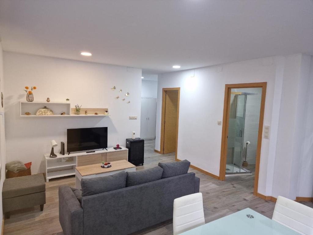 ein Wohnzimmer mit einem Sofa und einem TV in der Unterkunft La de Fredyy - Tres Marias Apartments in Redondela