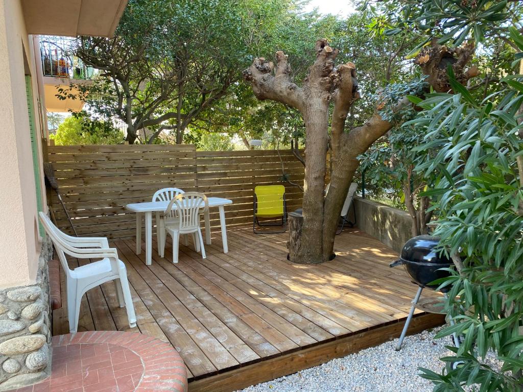 une terrasse en bois avec une table, des chaises et un arbre dans l'établissement studio avec parking et extérieur à 2 min de la plage, à Argelès-sur-Mer