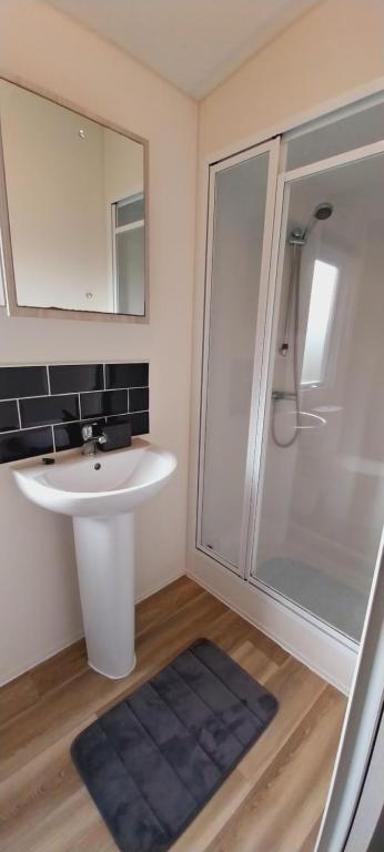 een badkamer met een witte wastafel en een douche bij WillowWay168, Tranquility Family Home in Camber
