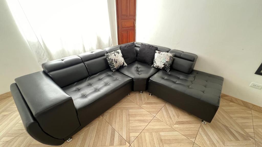 a black leather couch in a living room at Acogedor apartamento esquinero, a una cuadra del parque principal in Líbano