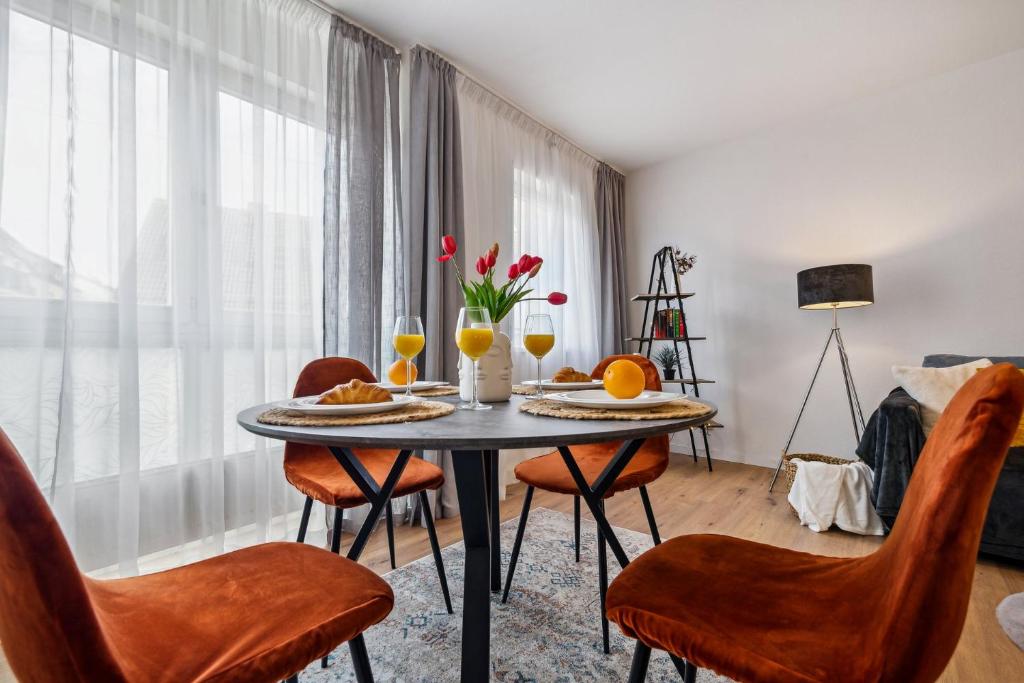 a dining room with a table with food and orange chairs at Comfort Apartment - bis 4 Pers - Neunkirchen City - Parkplatz - Garage - WiFi - Bad - Balkon in Neunkirchen