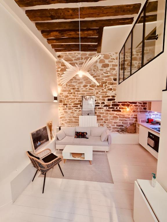 - un salon avec un canapé blanc et un mur en briques dans l'établissement Plein cœur de Paris : Charmant Duplex à Bastille, à Paris