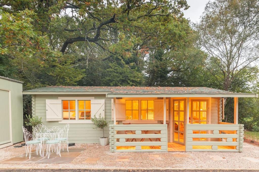uma pequena casa com janelas laranja e um alpendre em Family friendly sunny Log Cabin em Wimborne Minster