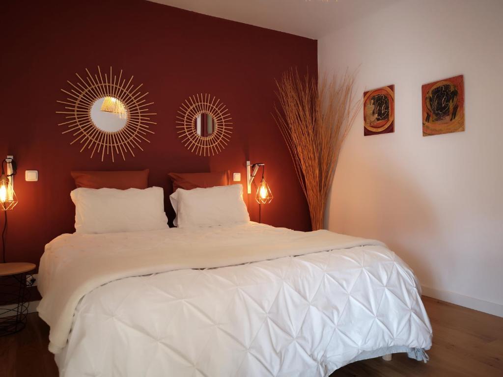 a bedroom with a large white bed and a mirror at Au Gray du temps suspendu in Pleslin-Trigavou