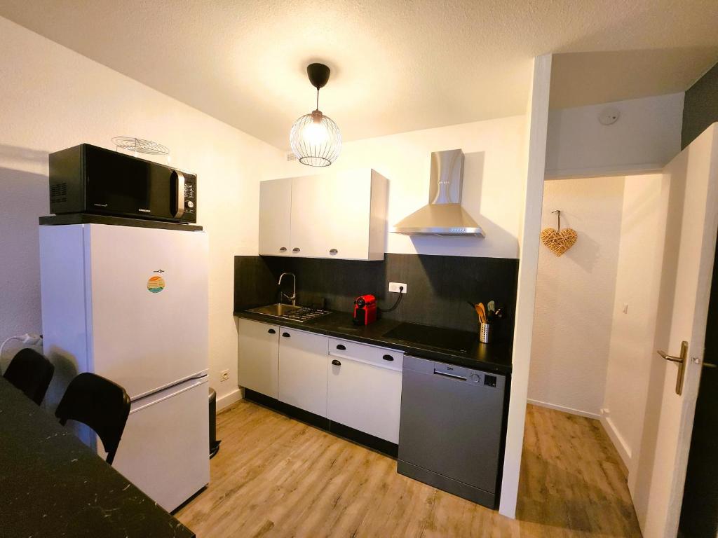 a kitchen with a white refrigerator and a black counter top at Appartement vue océan in Lacanau-Océan