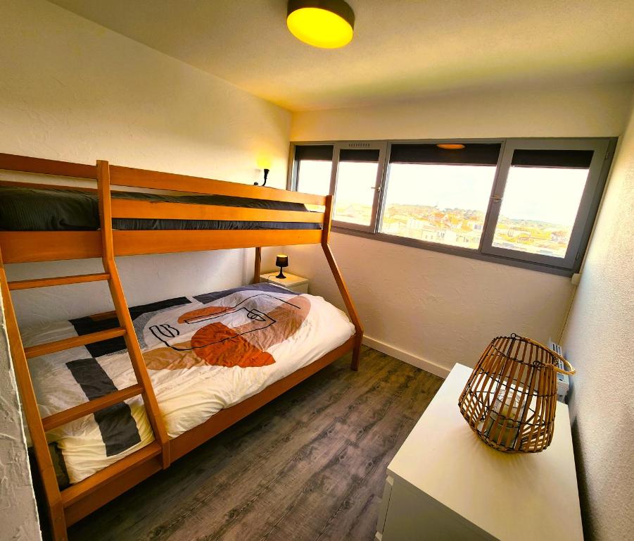 a bedroom with two bunk beds and a table at Appartement vue océan in Lacanau-Océan