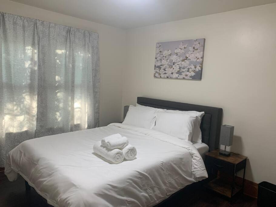um quarto com uma cama branca e toalhas em Lasalle Getaway Home! em Niagara Falls