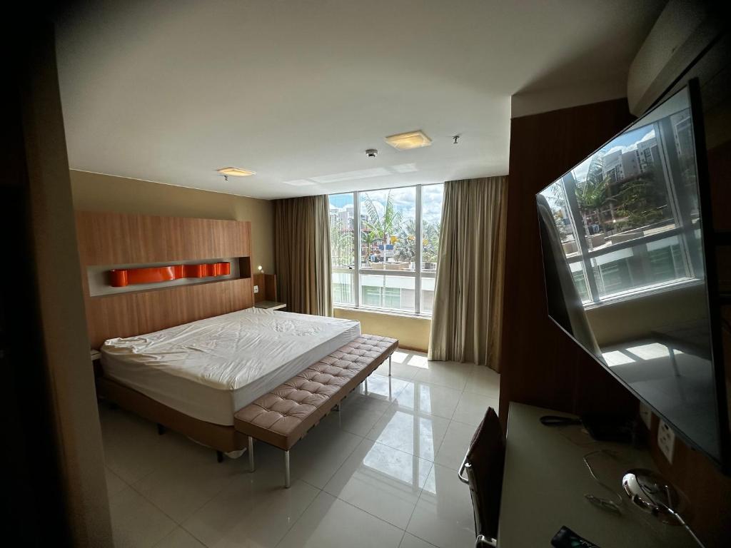 a bedroom with a bed and a large window at Flat no Jade in Brasilia