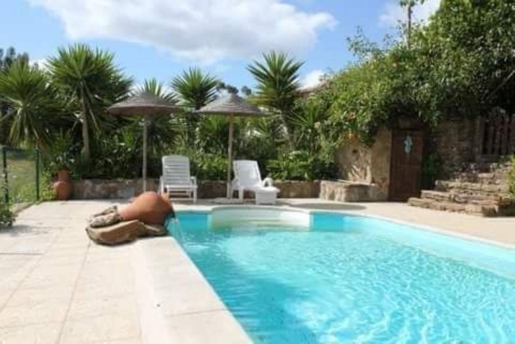 a swimming pool with a man laying on the ground next to it at Serra do Caldeirao Villa with Pool in Curvatos