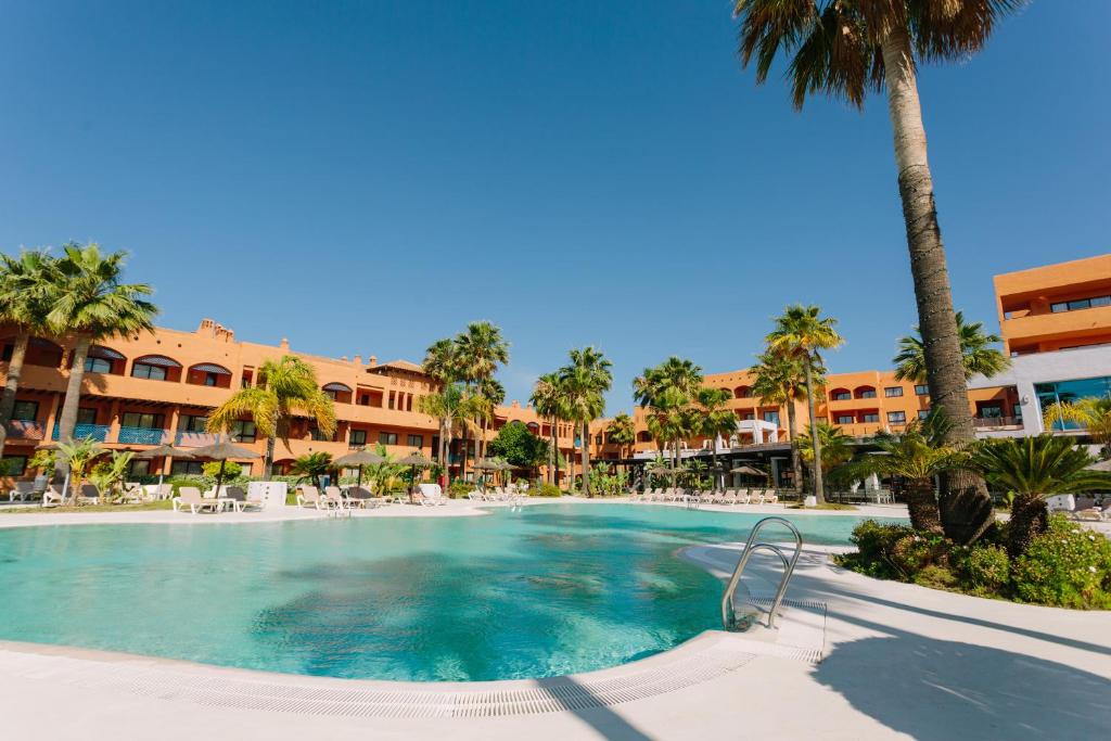 uma piscina num resort com palmeiras e edifícios em Hotel Oh Nice Caledonia em Estepona