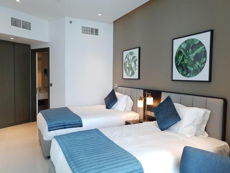 una camera d'albergo con due letti con cuscini blu di Lovely 2/ Bedroom apartment a Dubai