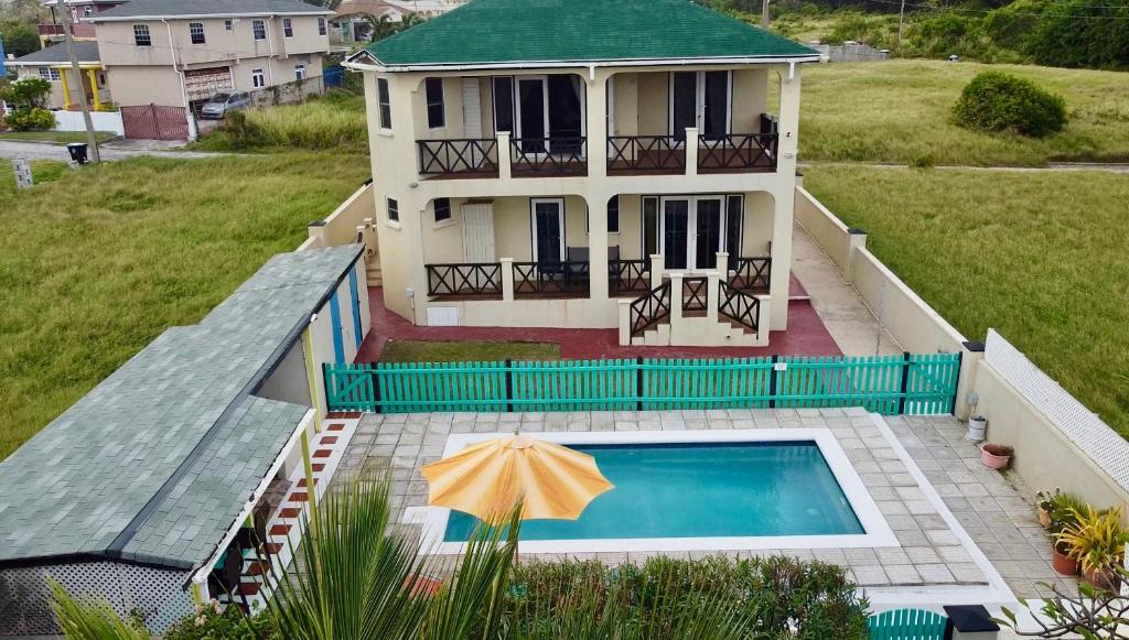 a house with a swimming pool and an umbrella at Lailamar Villa, Ocean view & Pool - Ground Floor in Saint Philip