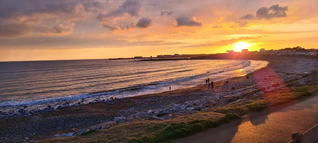 a sunset on a beach with the ocean at Thistle 83 in Porthcawl