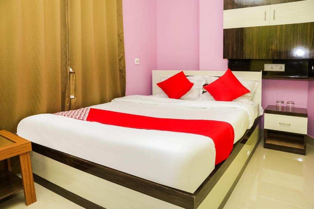 a bedroom with a large bed with red pillows at OYO Hotel Sonar Gaon in Agartala