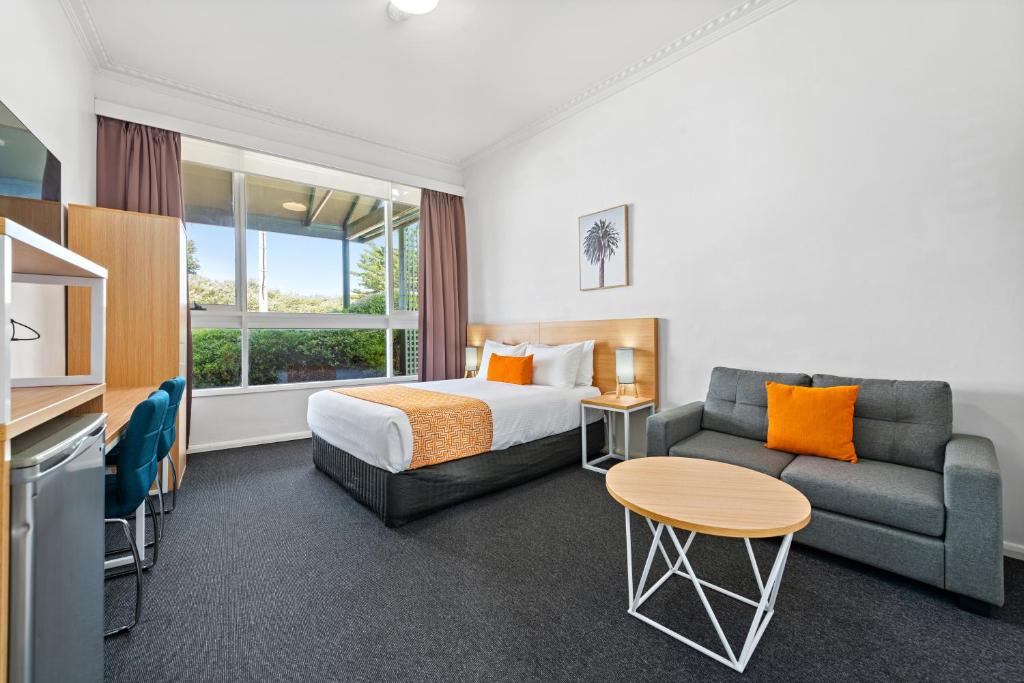 une chambre d'hôtel avec un lit et un canapé dans l'établissement Comfort Inn & Suites Lakes Entrance, à Lakes Entrance