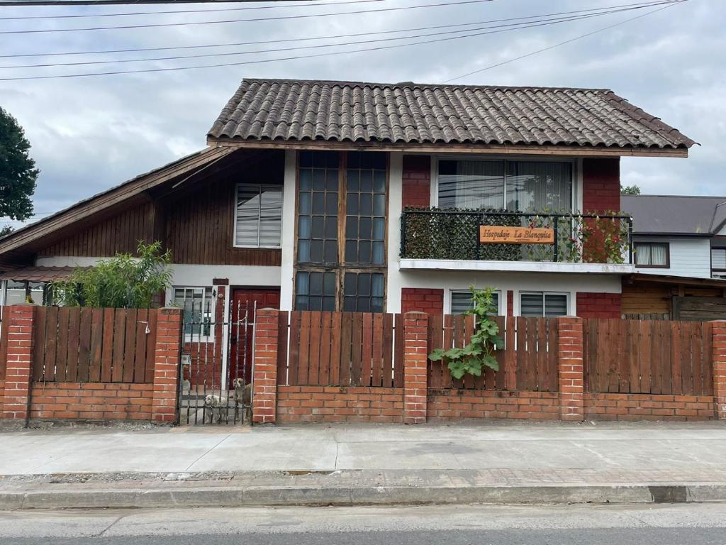 una casa de ladrillo rojo con una valla de madera en Hospedaje La Blanquita, en Santa Juana