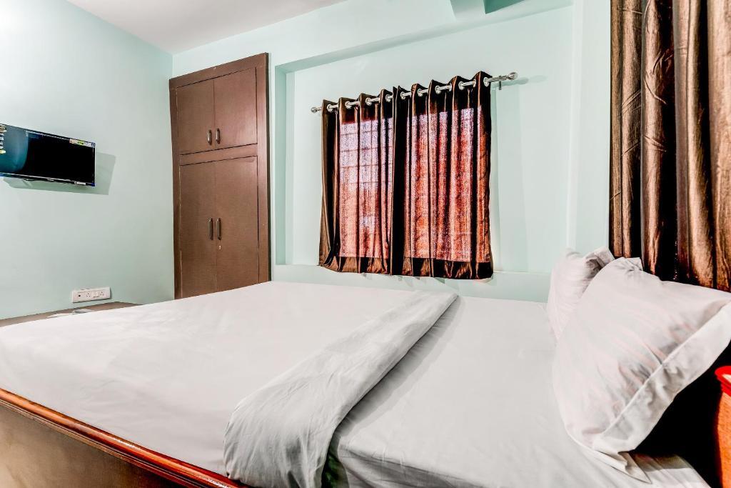 1 dormitorio con 1 cama blanca y ventana en Flagship Hotel Ashish Kiran, en Dhanbād