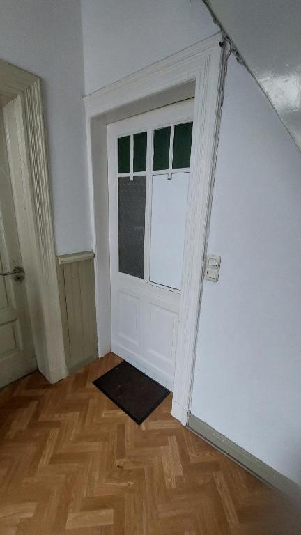 Cette chambre dispose d'une porte blanche et de parquet. dans l'établissement ferienwohnung Radevormwald Mitte, à Radevormwald