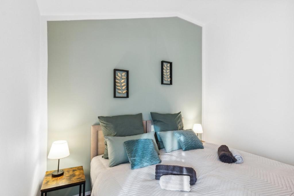 1 dormitorio con cama blanca y almohadas azules en Zigarrenhof Apartment in Citynähe inkl. Netflix, en Aschaffenburg