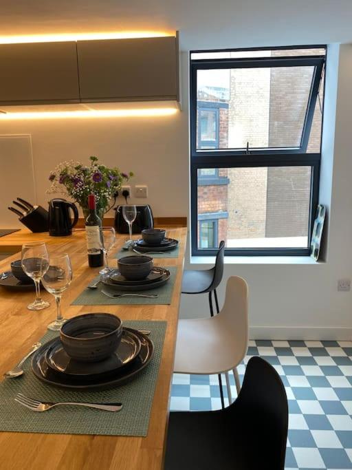 Hotel Contemporary City Centre 3 bedroom apartment, a dining room with a table with plates and wine glasses at Contemporary City Centre 3 bedroom apartment in Sheffield