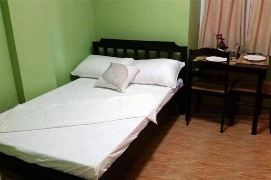 Bett in einem grünen Zimmer mit Tisch und Bett in der Unterkunft Jocanai Residences Studio C in Lusong