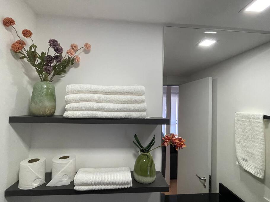 a bathroom with a shelf with towels and flowers at Apê 511 NEX ONE in Sao Paulo