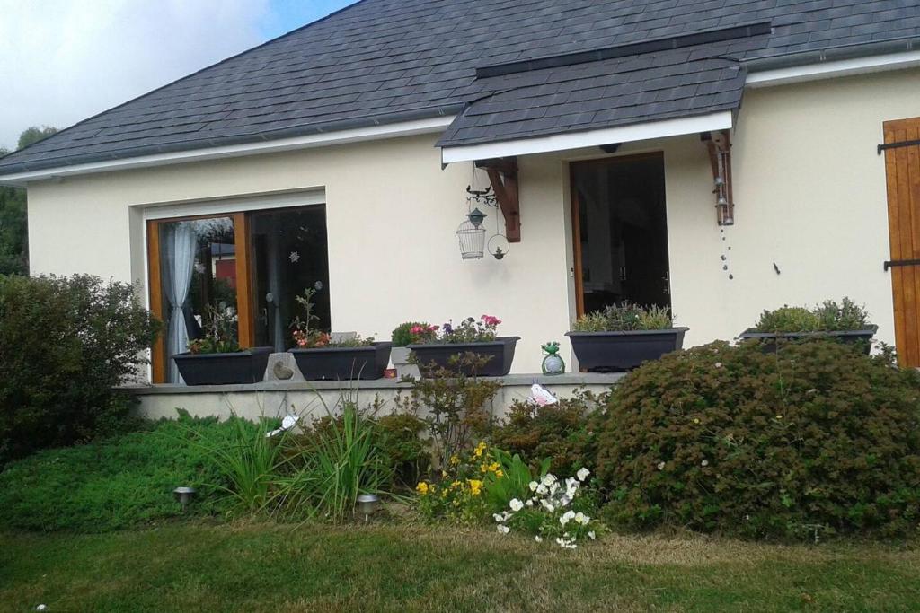 a white house with potted plants on the front porch at Propriete de 2 chambres avec terrasse et wifi a Liginiac a 5 km de la plage in Liginiac