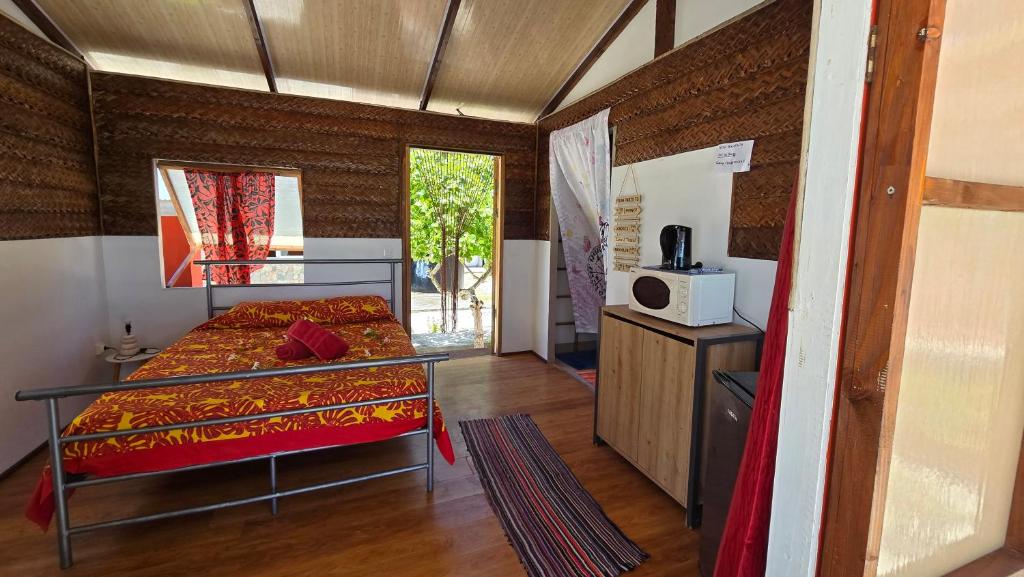 Habitación con cama y microondas. en Tikehau HereArii Airbnb en Tikehau