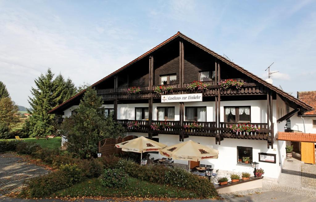 ein großes Gebäude mit Sonnenschirmen davor in der Unterkunft Gasthaus "Zur Einkehr" in Neureichenau