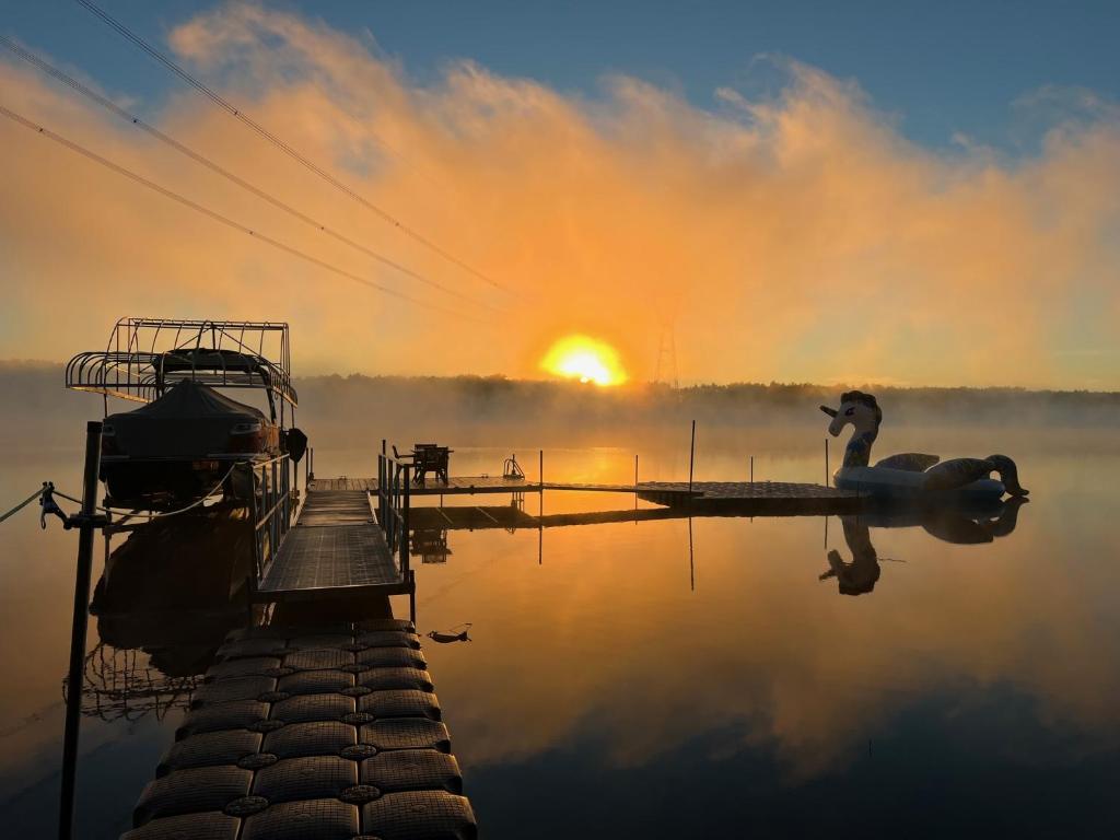 un cigno in piedi su un molo su un lago con il tramonto di Bright Amazing 6 Bed Chalet Waterfront in Rigaud a Rigaud