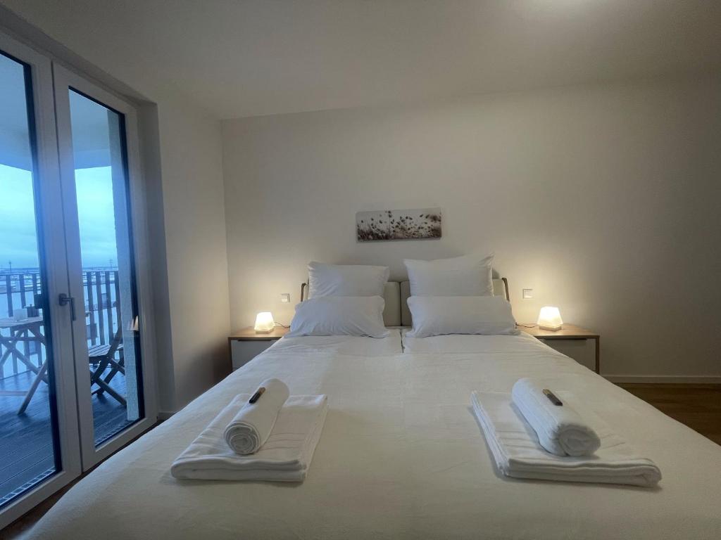 a bedroom with a large white bed with towels on it at Luxurious and stylish apartment at BER Airport in Schönefeld