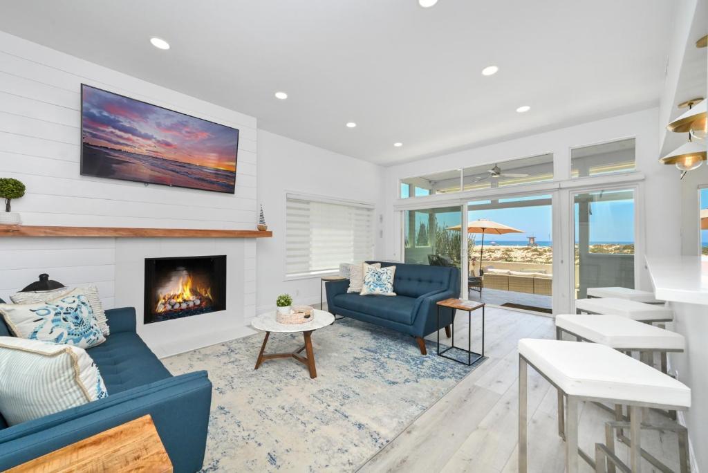 een woonkamer met een open haard en blauwe stoelen bij Brand new Lower unit on the Beach with Patio and Firepit in Newport Beach