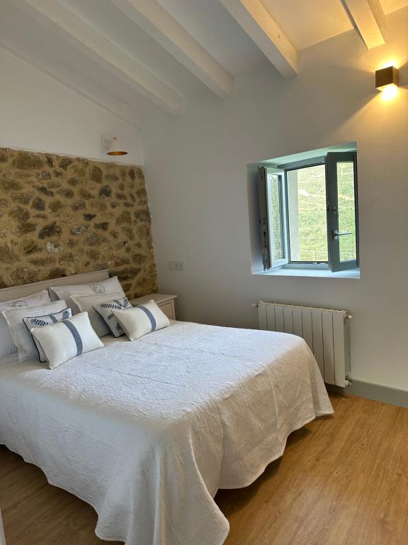 1 dormitorio con 1 cama blanca grande con almohadas en RUSTIC HOMES en San Vicente de la Barquera