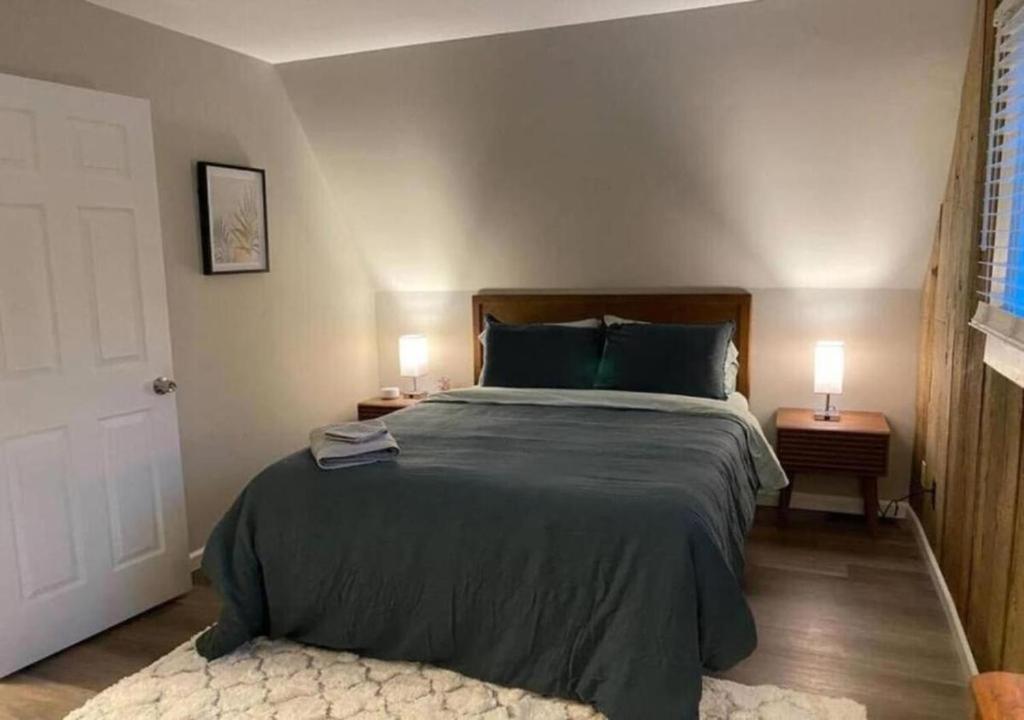 a bedroom with a large bed and two lamps on tables at 1BR Apartment near Ark Encounter with Parking in Dry Ridge
