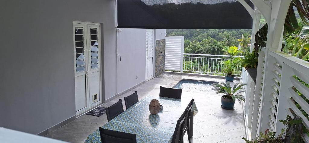 a balcony with a table and chairs and a pool at LOCATION LA MONTAGNE MARTINIQUE in Le Vauclin