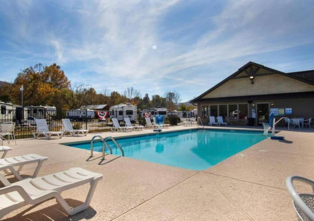 a swimming pool with chairs and a building at Picturesque Family Cabin with Loft in Tennessee in Sevierville