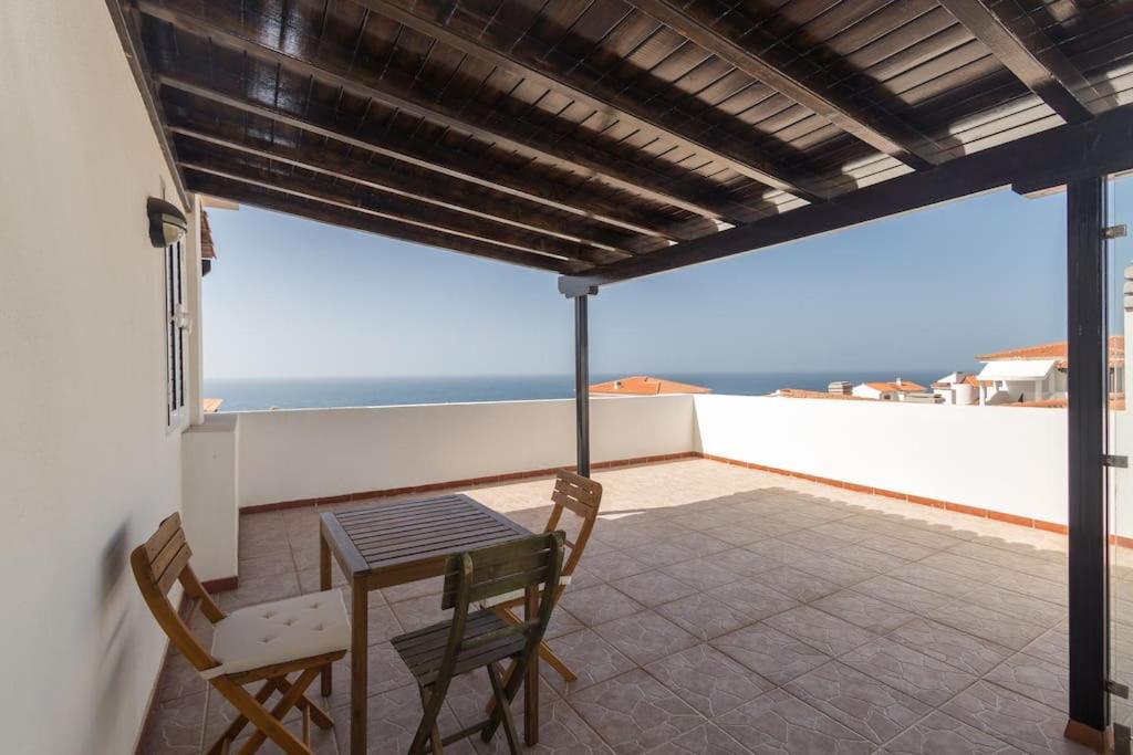 Una mesa y sillas en un balcón con vista al mar. en Ático con terraza en Agaete, en Agaete