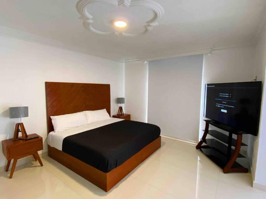 1 dormitorio con 1 cama y TV de pantalla plana en LA CASA BLANCA Suites Tepic SPA Familiar en Tepic