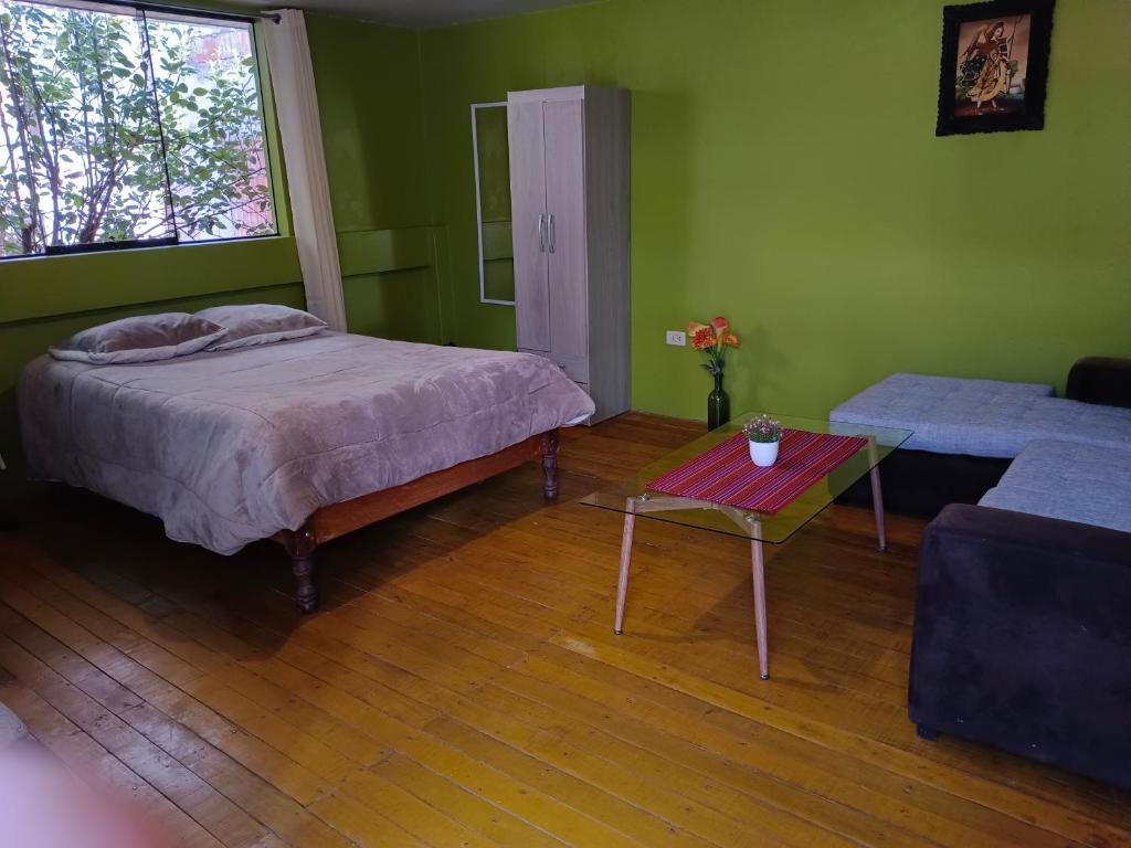 - une chambre avec un lit, une table et un canapé dans l'établissement Casa Victoria, à Cusco