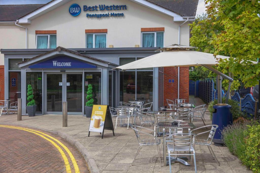 a restaurant with tables and chairs and an umbrella at Best Western Pontypool Metro Hotel in Pontypool