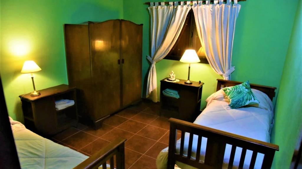 een slaapkamer met groene muren en 2 bedden en 2 lampen bij Sueño Iberá in Colonia Carlos Pellegrini