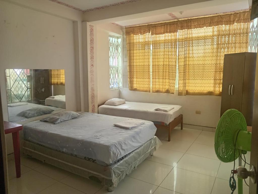 a bedroom with two beds and a desk and windows at HOSPEDAJE MARISCAL CASTILLA in Tumbes