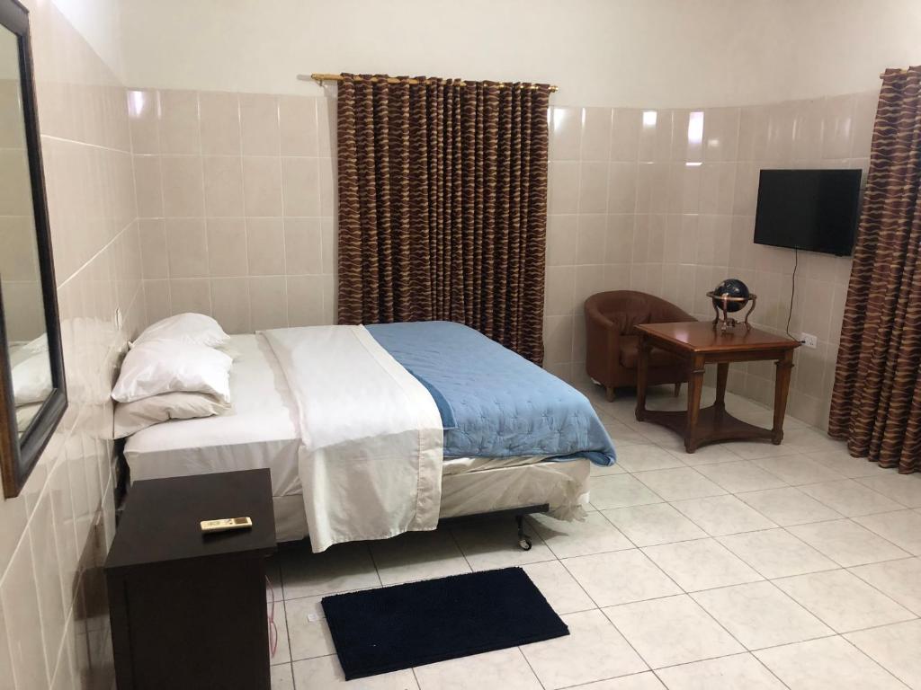 Private Rooms In Osu في آكرا: غرفة نوم بسرير وكرسي وتلفزيون