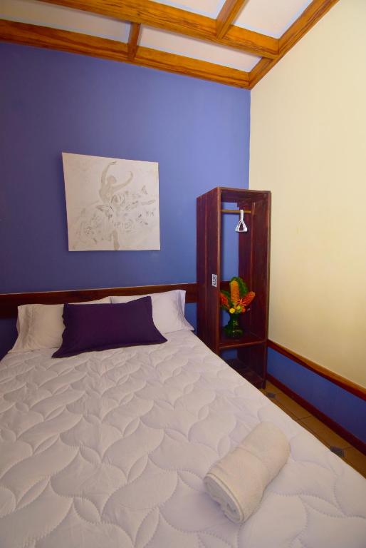 a bedroom with a large white bed with a blue wall at Hotel La Riviera in Sabalito