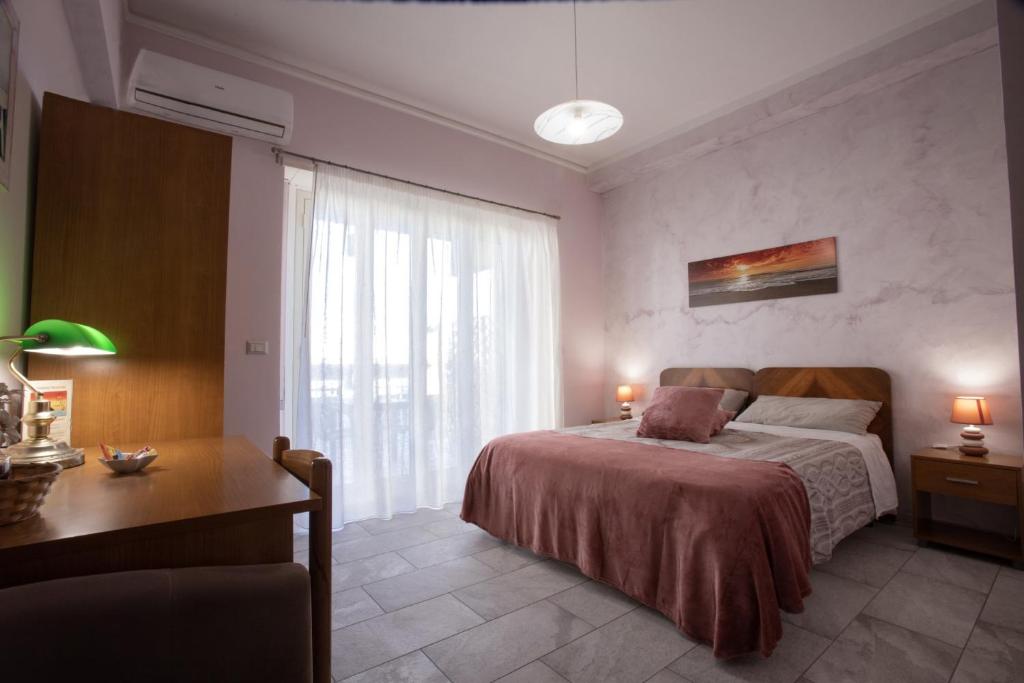 a bedroom with a bed and a desk and a window at Etna Sea House in Catania