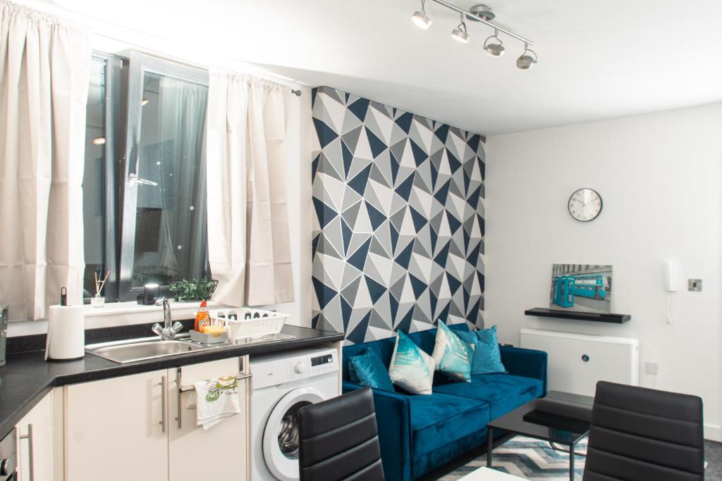 a living room with a blue couch in a kitchen at Charming and Bright 2 Bedroom Apartment, Close to Stadiums, Transport links, Free Parking in Manchester