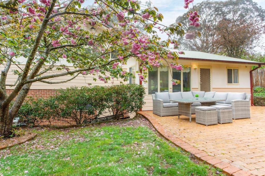 カトゥーンバにあるStunning Katoomba Home with Lush Garden&Playgroundの家の前にソファとテーブル付きのパティオ